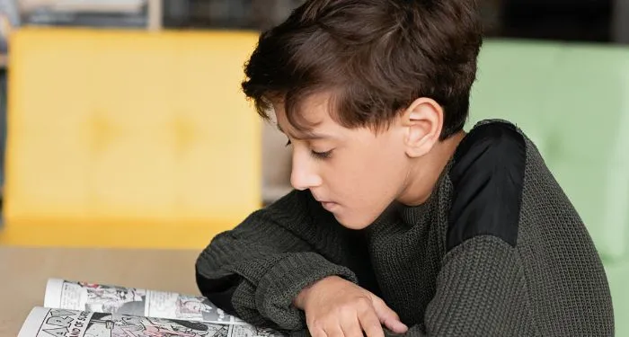 child with white skin reading a comic book or graphic novel